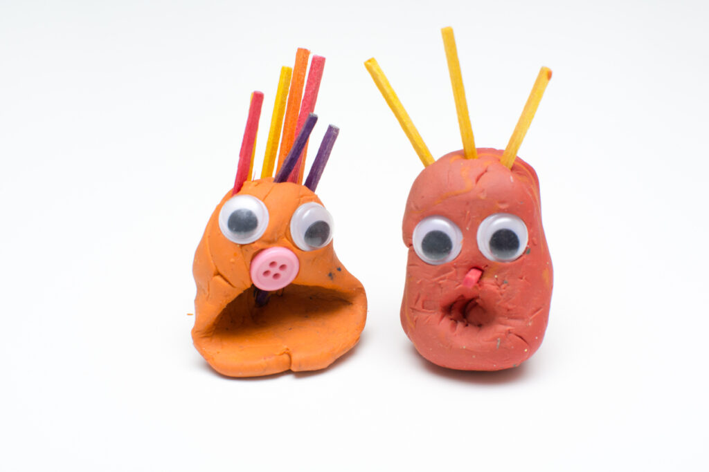 Fun modelling clay figures with shocked expression on isolated white background.
